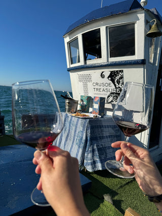 Dos copas de vino del mar crusoe treasure brindando en barco con el mar al fondo