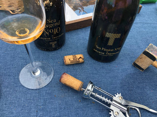 Sacacorchos con corcho enroscado en mesa con mantel azul y dos botellas de crusoe treasure de vino